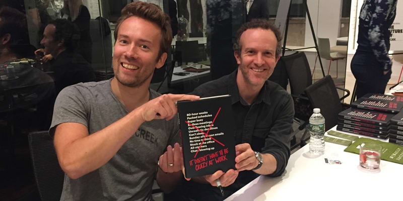 Basecamp founders Jason Fried and David Heinemeier Hansson holding their book It Doesn’t Have to Be Crazy at Work at a book signing event.