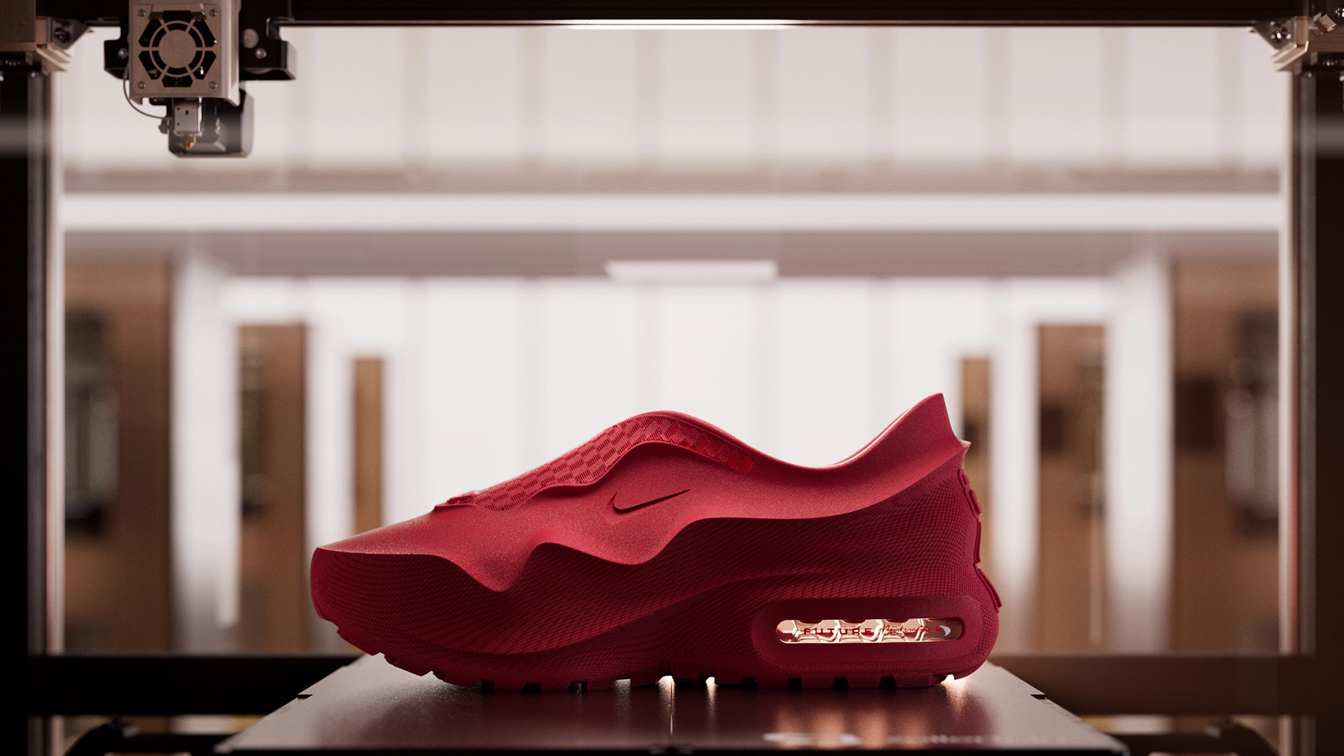 Red Nike Air Max 1000 prototype displayed on a 3D-printing platform, highlighting its sculpted design and visible Air cushioning unit.