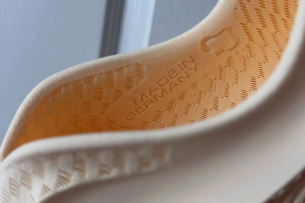 Nike Prototype Running Shoe in Motion – Tumisang Bogwasi Close-up of a hand holding a modern Nike running shoe featuring a knit upper and sculpted sole against a blurred urban background.