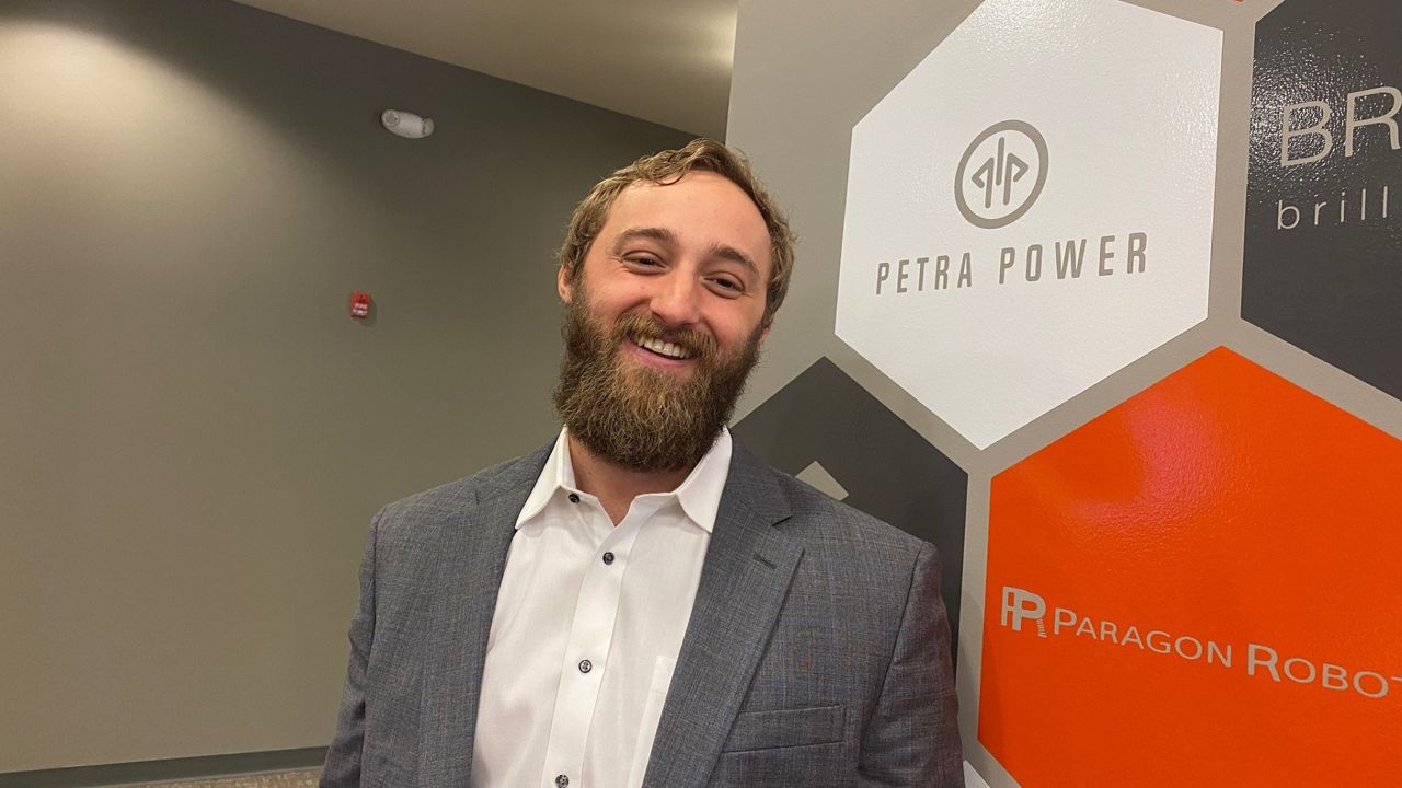 Petra Power Co-Founder Aaron Goodman at Company Headquarters – Tumisang Bogwasi Aaron Goodman, co-founder of Petra Power, smiling in front of a Petra Power logo wall at the company's headquarters.