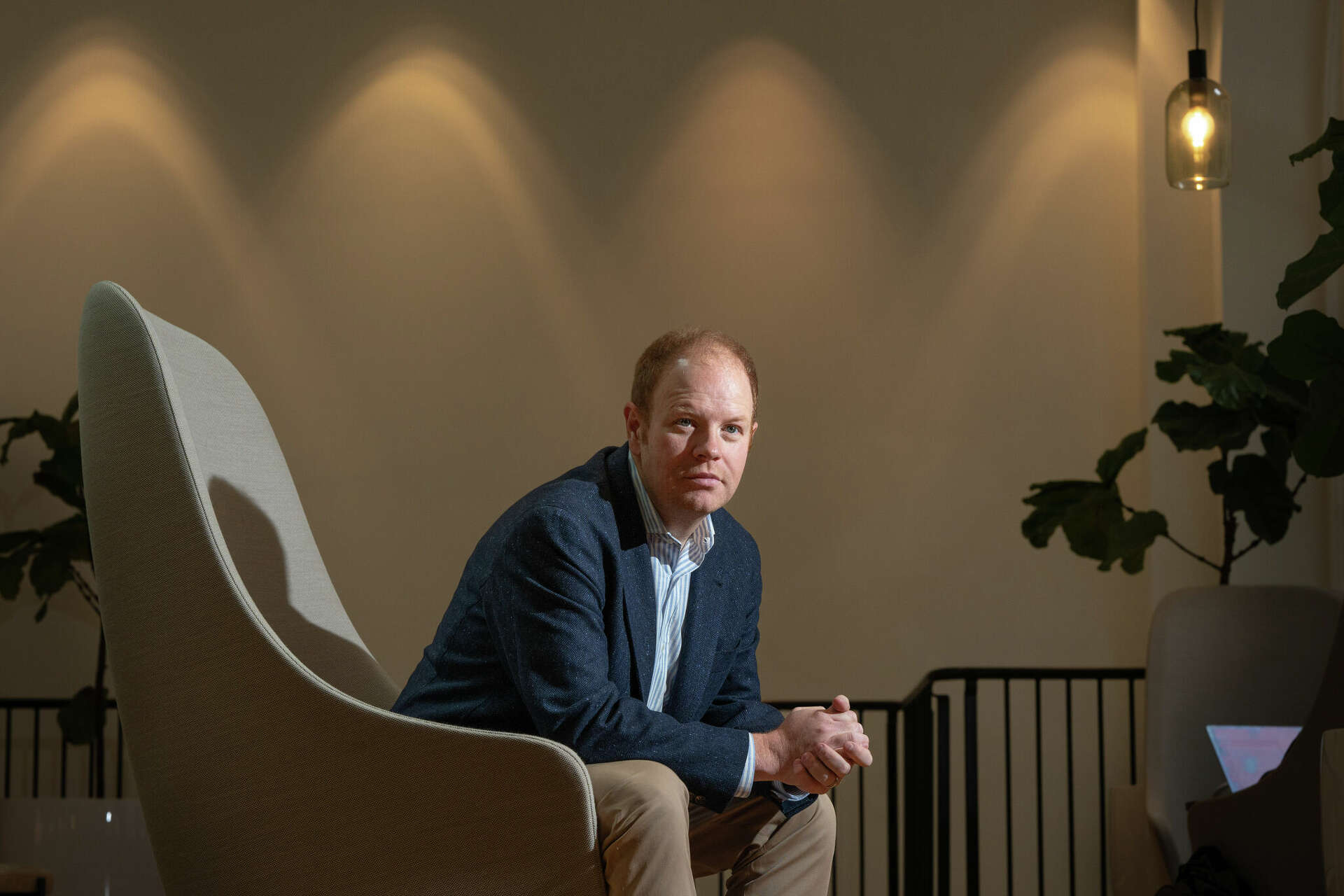 Parker Conrad Founder and CEO of Rippling – Tumisang Bogwasi Parker Conrad, founder of Rippling, seated in a high-backed chair in a softly lit office environment, looking toward the camera.